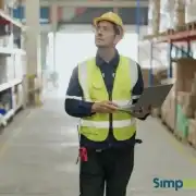 Facility Management Integrado | Simplia Trabajador con casco y chaleco reflectante utiliza una computadora portátil en un depósito.